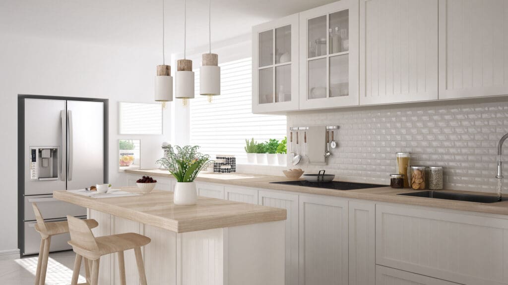 Modern kitchen with light wood cabinets, island with stools, pendant lights, a built-in fridge, sink, stovetop, and various kitchen items on the countertops. Bright natural light streams through a large sash window, recently restored with expert sash window repairs.